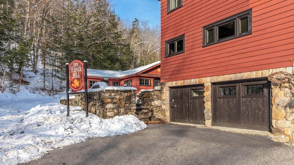 A red building with stone walls, a sign for The Inn at Turner Mill, and a snow-covered landscape.