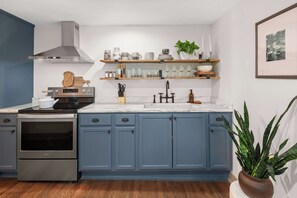 A modern kitchen with blue cabinets, stainless steel appliances, and a marble countertop. - Stowe Dual Condo | 4BR Mountain & River Retreat (Stowe)