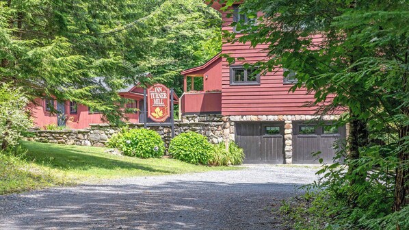 A red building with a stone wall and a sign for The Inn at Turner Mill.