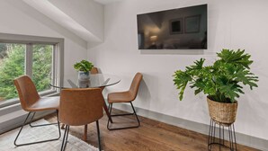 Un comedor moderno con una mesa de vidrio, sillas de cuero y una planta grande en maceta.