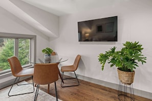 A modern dining area with a glass table, leather chairs, and a large potted plant. - Vermont 2BR | Stowe Slopes & Swimming Holes (Stowe)