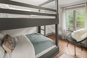 A bunk bed with white bedding, a patterned throw blanket, and a chair with a white furry cushion. - Vermont 2BR | Stowe Slopes & Swimming Holes (Stowe)