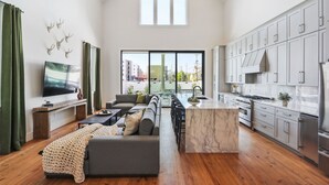 Un amplio espacio de estar con un sofá grande, un televisor y una cocina equipada con electrodomésticos modernos.