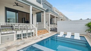 Zona junto a la piscina con una parrilla, asientos exteriores y piscina.