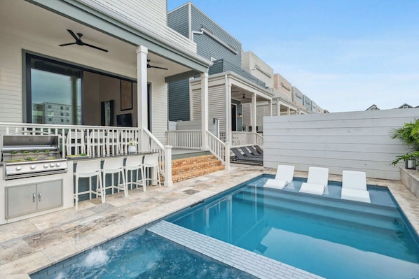 A poolside area with a barbecue grill, outdoor seating, and a pool.