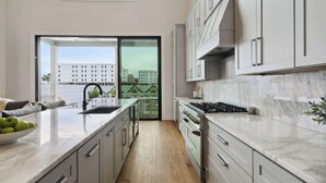 Una cocina moderna con un ventanal grande, estufa integrada y vistas a un paisaje urbano.