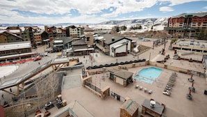 Un complejo de esquí con zona de piscina, mobiliario exterior y vistas a la montaña.