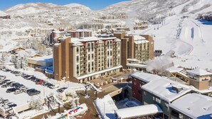 A high-rise hotel with multiple floors, a parking lot, and a ski slope in the background. - SV605 | Good Views | Ski In/Out | Pool | Hot Tub | A/C (Steamboat Springs)