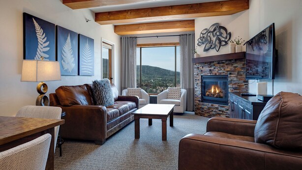 A cozy living room with leather sofas, a coffee table, a fireplace, and artwork on the walls. - SV605 | Good Views | Ski In/Out | Pool | Hot Tub | A/C (Steamboat Springs)