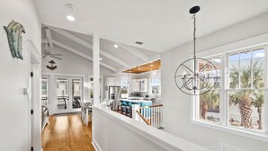 A spacious kitchen with a large island, white cabinetry, and a view of palm trees outside. - Bay Views with Pool and Gym Access (Port St. Joe)
