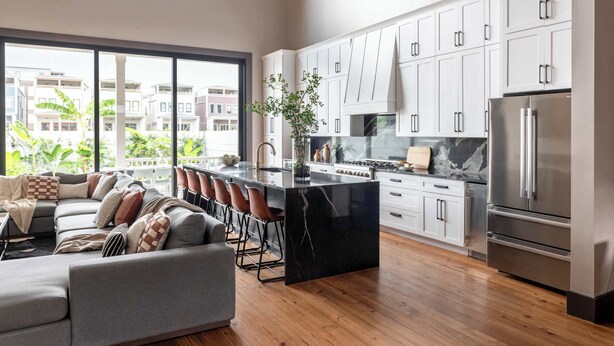 A modern kitchen with white cabinets, a large island, and a stainless steel refrigerator. - The 1300 | 7 Bedroom Luxe Home, Heated Pool & Spa (New Orleans)