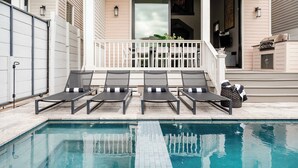 A poolside area with lounge chairs and a barbecue grill. - The 1300 | 7 Bedroom Luxe Home, Heated Pool & Spa (New Orleans)