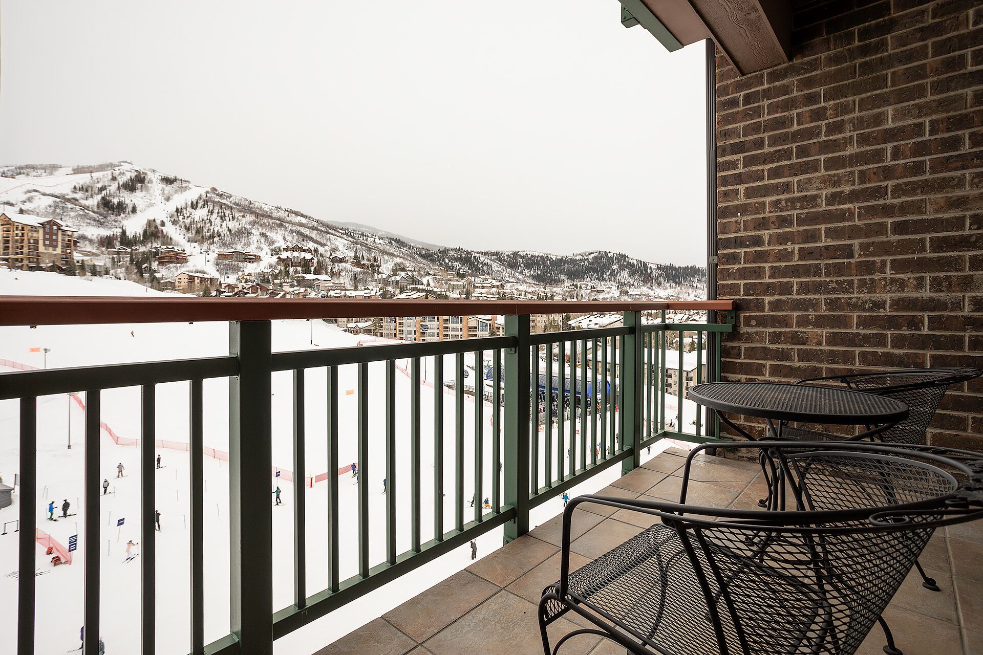 A balcony with a view of a snow-covered mountain and a ski resort.