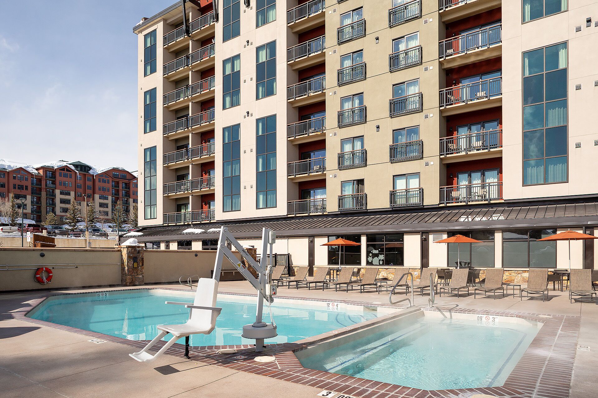 A hotel with a pool area, including lounge chairs and umbrellas.