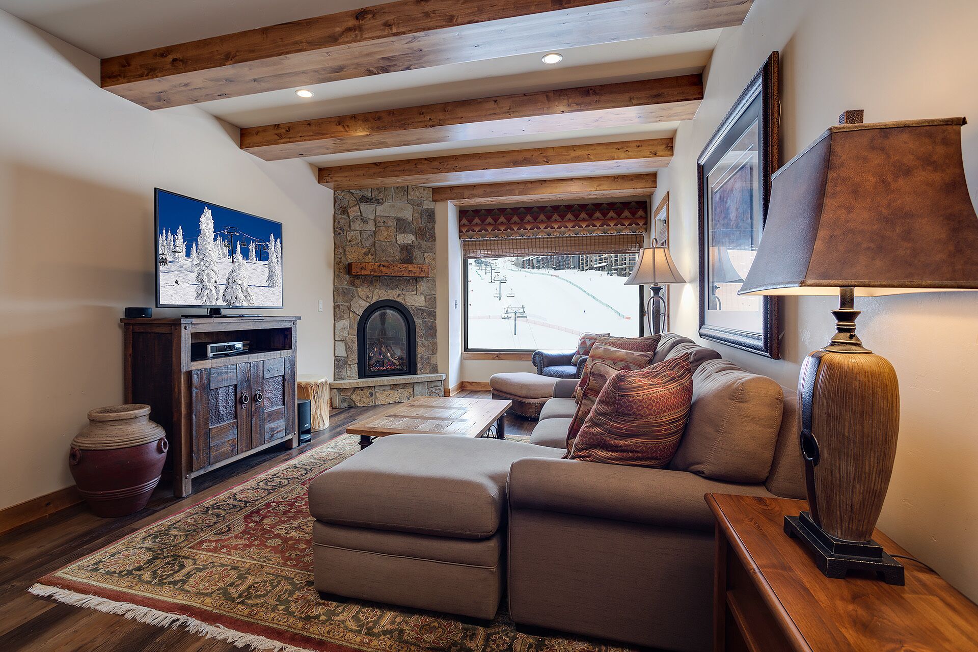 A cozy living room with a fireplace, a large window, and a television on a wooden cabinet.