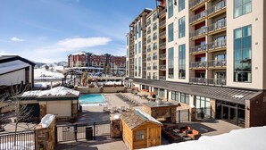 Un hôtel doté d’une piscine, d’un espace extérieur aménagé et offrant une vue sur une station de ski en arrière-plan.