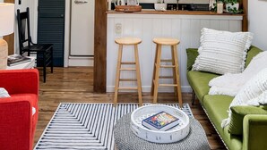 Et hyggeligt køkken med træbjælker, et spiseområde med en rød stol og en grøn sofa.