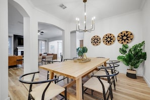 Un espace repas comprenant une table en bois, des chaises, un lustre et des œuvres d’art décoratives murales.