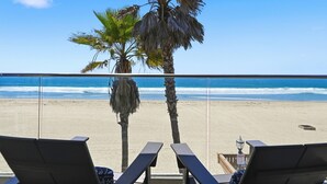 A beach view with palm trees, a clear sky, and lounge chairs.