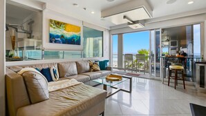 A modern living room with a leather sofa, glass coffee table, and a painting on the wall.