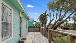 A turquoise house with a wooden deck and a fenced porch.