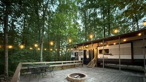 Una terrazza coperta con un braciere, posti a sedere all'aperto e un camper.