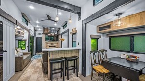 Una cucina moderna con isola centrale, sgabelli da bar e tavolo da pranzo con sedie.