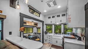 Una cucina moderna con mobili bianchi, un'isola centrale e un'area pranzo con una panca.