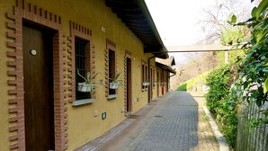 A yellow building with brick accents, a paved pathway, and potted plants. - AGRITURISMO FOREST B&B (Iseo)