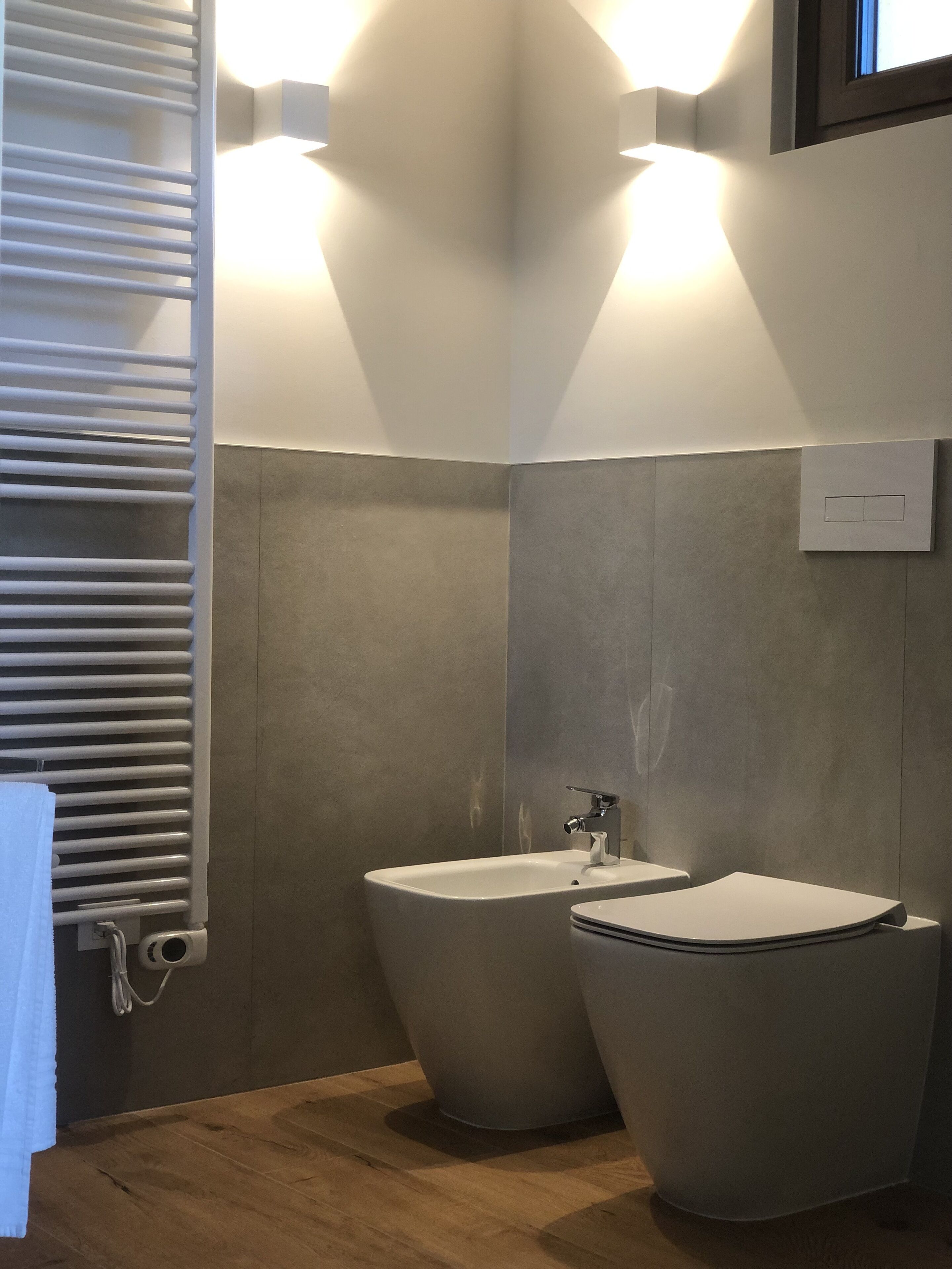 Ein Badezimmer mit zwei Waschbecken, einem Handtuchhalter und einem Lichtschalter an der Wand.