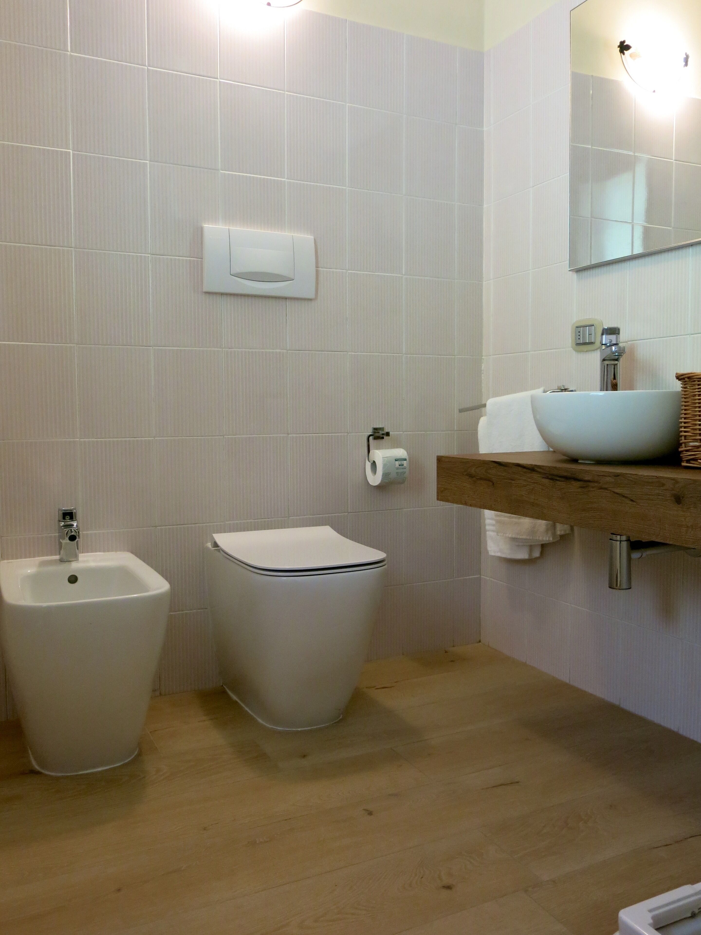 Een badkamer met een hygiëneslot, toilet en een wastafel met spiegel erboven.