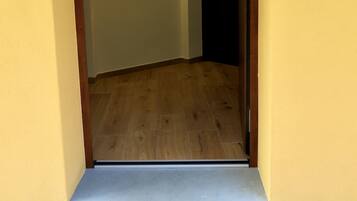 Un pasillo con piso de madera, una puerta con picaporte y dos luces fijadas a la pared.