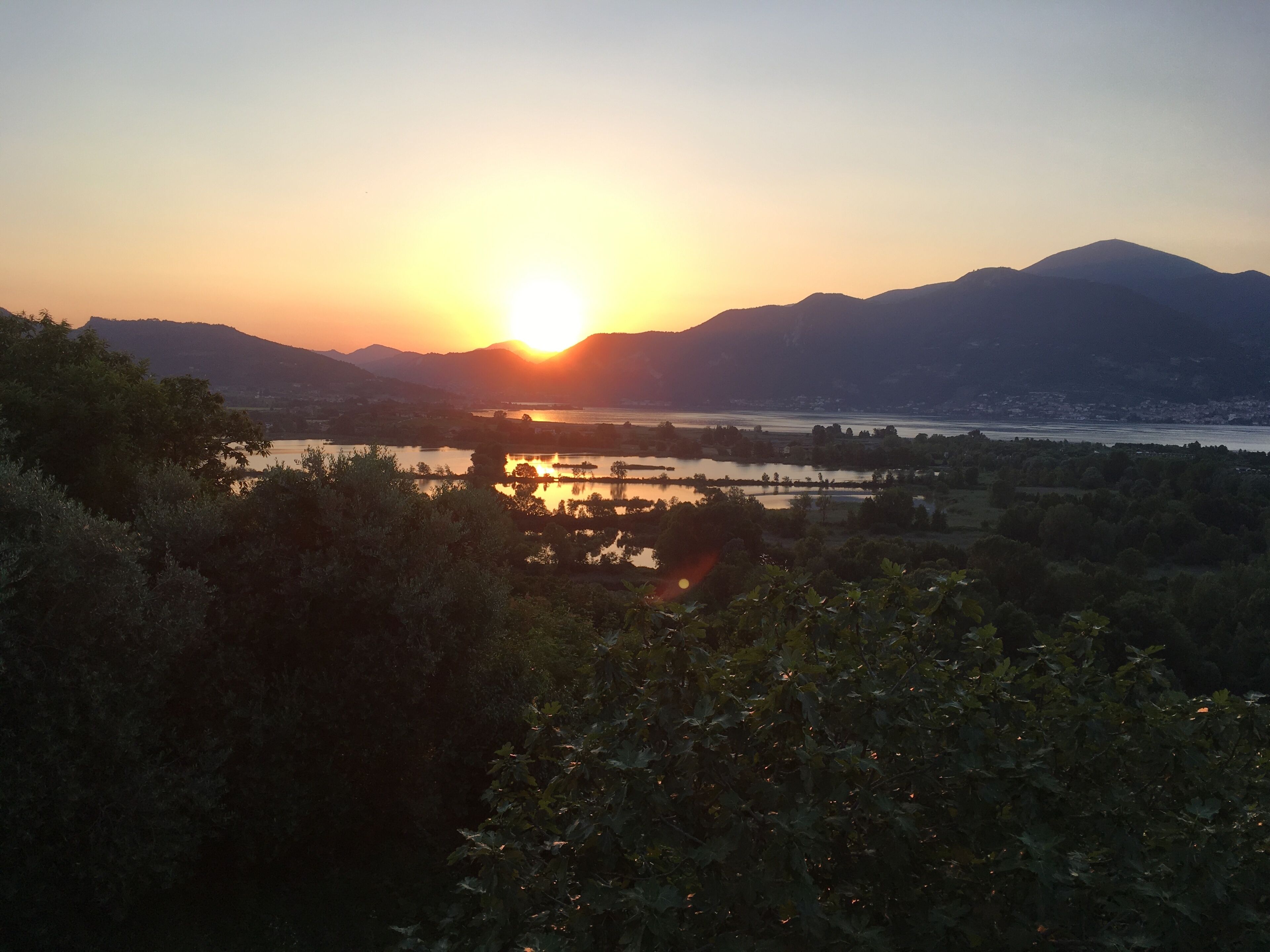 A sunset over a river with mountains in the background.