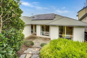 Stylish home with solar panels, large windows, and a lush garden.