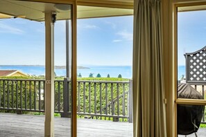 Relax on the deck with a view of the sea, featuring a seating area and glass door with a curtain for a retreat.