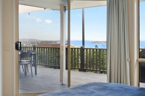 Enjoy a room with a balcony offering a view of the sea and distant shoreline, featuring a table and two chairs.