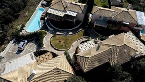 Vogelperspektive auf ein Wohngebiet mit Swimmingpool, geschwungenen Auffahrten und mehreren Häusern mit Ziegeldächern.