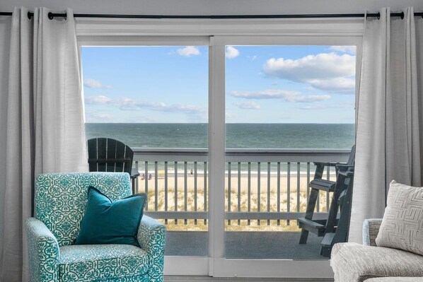 A room with a large sliding glass door leading to a beach view.