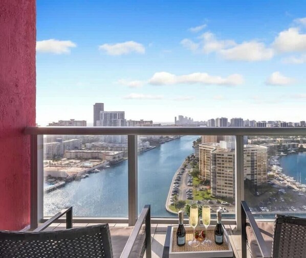 A balcony with a view of a river, buildings, and a marina.
