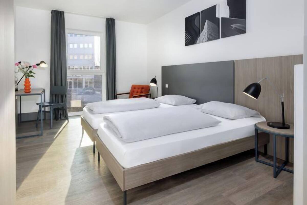 A modern hotel room with a large bed, a desk, and a chair.