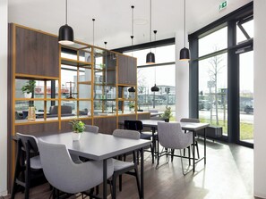 A modern dining area with tables and chairs, large windows, and a view of the street.