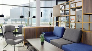 A modern office space with a seating area, a wooden desk, and a bookshelf. - smartments Frankfurt City-Ost (Frankfurt)