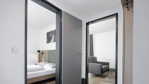 A modern hotel room with a bed, a chair, and a desk. - smartments Frankfurt City-Ost (Frankfurt)