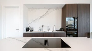 Une cuisine moderne avec un dosseret en marbre, des meubles en bois foncé et un four encastré.