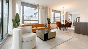 Un salon moderne comprenant un canapé, une table basse et un coin repas avec des chaises.