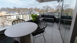 Un balcon avec une table ronde et des chaises, un canapé et une plante en pot.