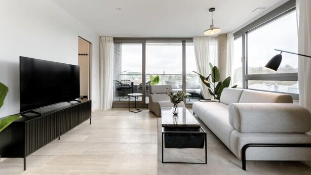 Una sala de estar moderna con un televisor de pantalla plana, un sofá, una mesa de centro y un comedor con una mesa y sillas.