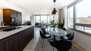 Una cocina moderna con una isla central, sillas negras y una mesa de comedor con un florero.