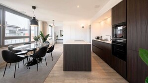 Una cocina moderna con armarios de madera oscura, una isla central y un comedor con sillas negras.