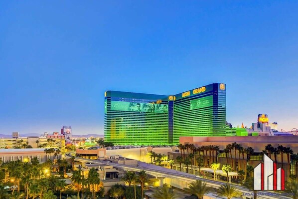 A large hotel with multiple high-rise buildings, featuring prominent signage and a well-lit facade. - MGM Signature-07-620 1Br 2Ba Balcony Suite (Las Vegas)